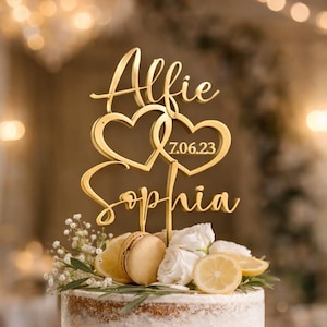 Op de afbeelding: Een drielaagse naked cake versierd met witte rozen, citroenschijfjes en groen. Een goudkleurige taarttopper toont de namen Alfie en Sophia in cursief schrift, twee in elkaar grijpende harten en de datum 7.06.23 in een strak lettertype.