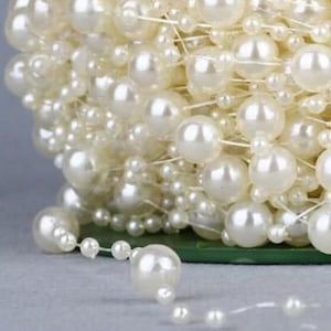 May include: A spool of white pearl garland with varying sizes of pearls. The garland is made of a clear string and is perfect for adding a touch of elegance to any occasion.