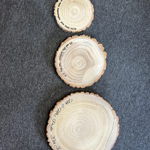 May include: Three circular wooden slices with natural bark edges, each featuring wood-burned text. The smallest reads Mr & Mrs Thompson 6th June 2024, the middle reads Mr and Mrs Tomlinson 2nd May 2026, and the largest reads Mr & Mrs Pryke 20th June 2026.