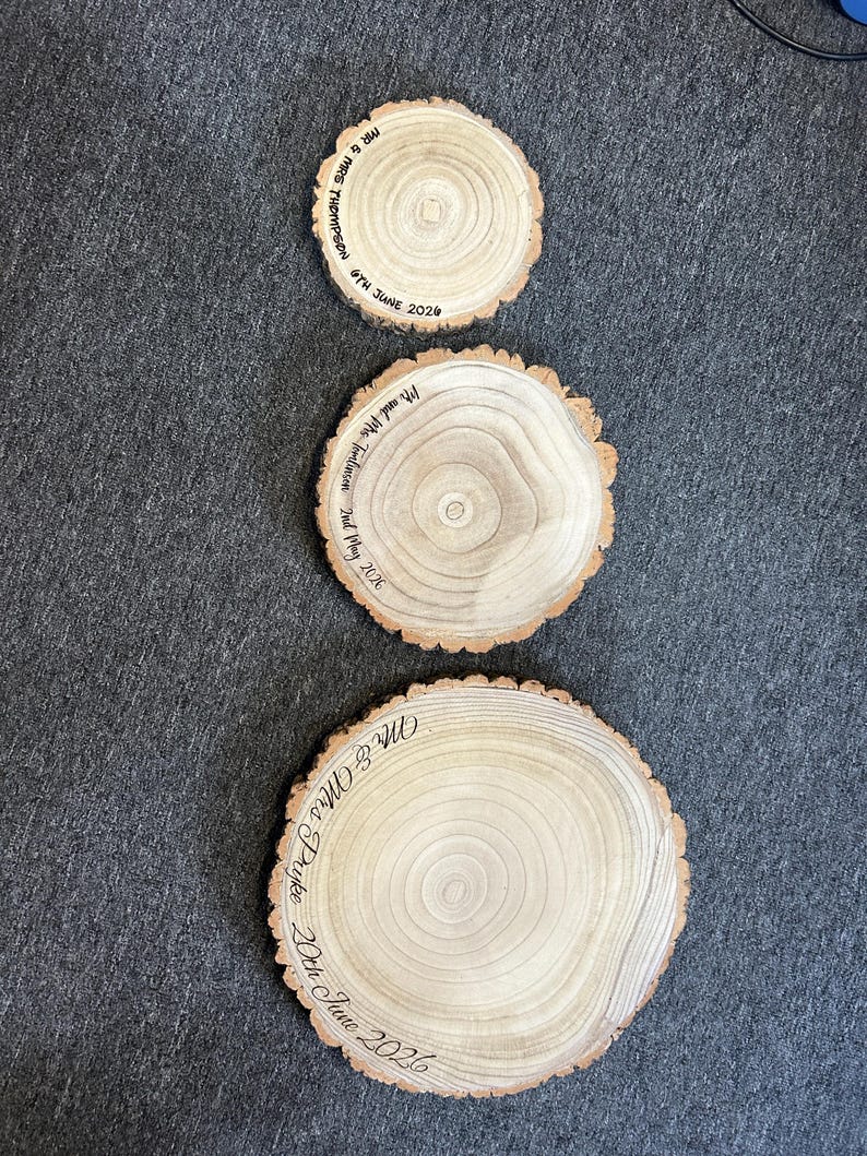 May include: Three circular wooden slices with natural bark edges, each featuring wood-burned text. The smallest reads Mr & Mrs Thompson 6th June 2024, the middle reads Mr and Mrs Tomlinson 2nd May 2026, and the largest reads Mr & Mrs Pryke 20th June 2026.