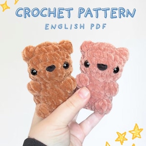 May include: Two small plush bear figures made of soft brown and dusty pink yarn. The text CROCHET PATTERN ENGLISH PDF is displayed at the top. The bears feature round ears, black plastic eyes, and stitched noses. Yellow star graphics decorate the corners.