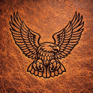 May include: A detailed, embossed image of an eagle with outstretched wings on a textured, brown leather surface. The eagle is depicted with sharp talons and a focused gaze, showcasing intricate feather details. The leather has a warm, aged appearance.