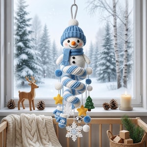 Può includere: Una decorazione sospesa all'uncinetto a forma di pupazzo di neve con un berretto in maglia blu, una sciarpa abbinata e un corpo a spirale. L'ornamento include elementi pendenti come stelle gialle, muffole blu, fiocchi di neve e un albero verde.