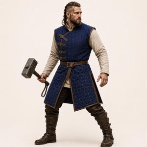 May include: A dark blue quilted sleeveless tunic with brown leather straps and buckles, worn over a beige long-sleeved shirt and dark brown trousers. The outfit includes tall brown leather boots with multiple buckles and a large metal hammer.