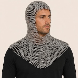 May include: A silver chainmail coif, covering the head and shoulders. The coif is made of small, interlocking metal rings, creating a flexible yet protective garment. The coif is worn over a black long-sleeved shirt.