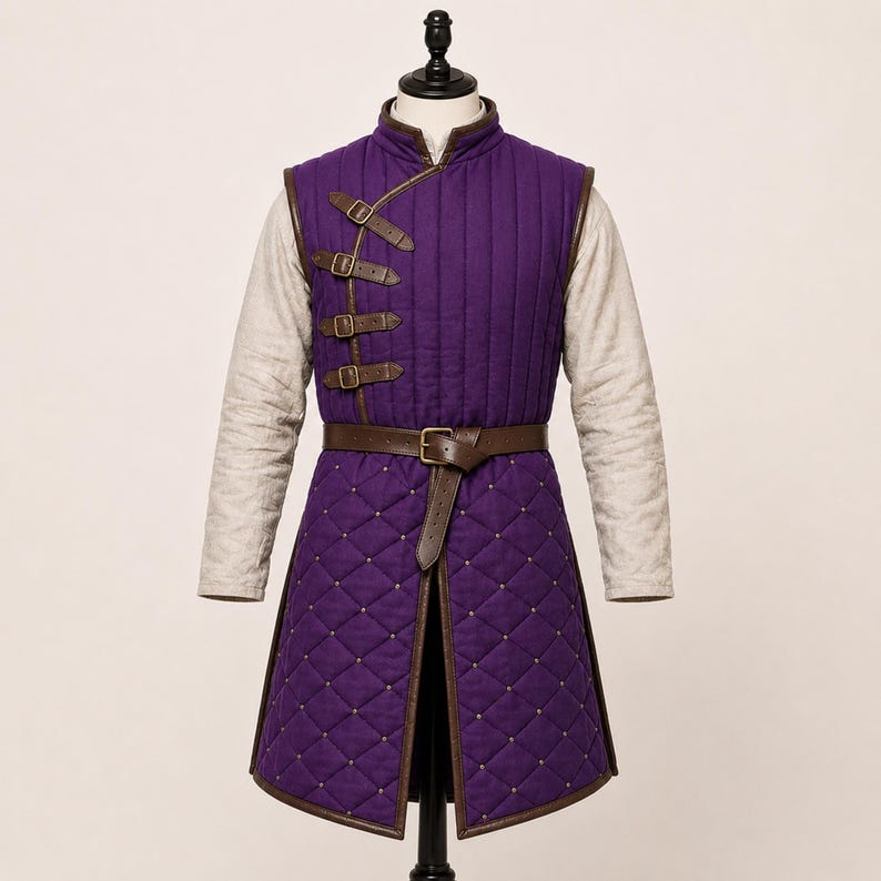 May include: A purple quilted vest with a high collar and long beige sleeves. The vest features vertical stitching on the chest, a diamond-quilted skirt, brown leather trim, four side-buckle closures, and a brown leather waist belt with a buckle.