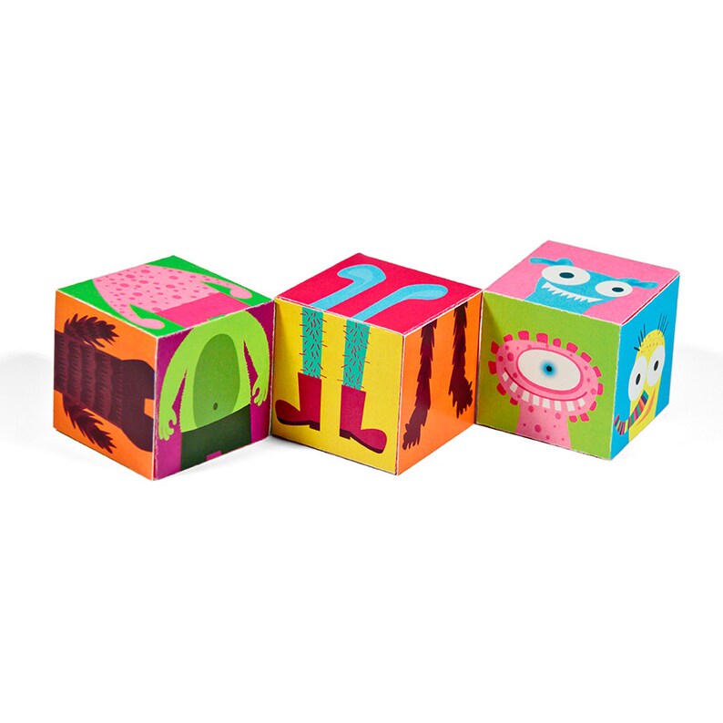 K&ouml;nnte beinhalten: Drei bunte Holzw&uuml;rfel mit verschiedenen Monsterdesigns auf jeder Seite. Die W&uuml;rfel zeigen ein pinkfarbenes Monster mit gr&uuml;ner Hose, ein blaues Monster mit gelben Beinen und ein gr&uuml;nes Monster mit einem rosa Auge.