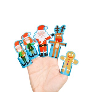 Pode incluir: Um conjunto de cinco fantoches de dedo com um homem de gengibre, Papai Noel, um duende, uma rena e uma duende. Os fantoches são feitos de papel e têm um fundo azul.