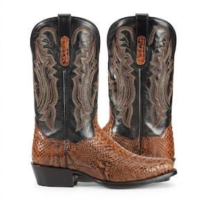May include: A pair of black and brown western boots featuring a textured snakeskin-patterned foot and a black shaft with intricate brown stitching. The boots include pull tabs at the top and a stacked heel, showcasing a classic pointed toe design.