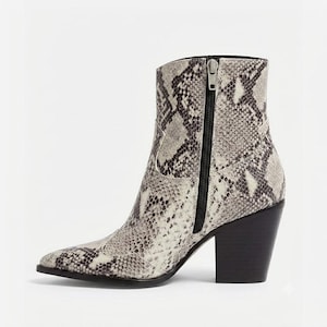 May include: An ankle boot featuring a grey and black snakeskin pattern, a pointed toe, and a solid black block heel. The boot includes a vertical black zipper closure on the side with a silver-toned metal pull tab and a structured shaft design.
