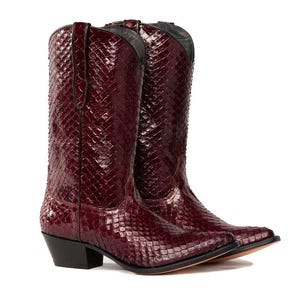 Könnte beinhalten: Burgunderfarbene Cowboy-Stiefel mit einer strukturierten, schlangenlederartigen Musterung. Die Stiefel haben spitze Zehen, schwarze Absätze und eine klassische Western-Silhouette, ideal für einen rustikalen Look.