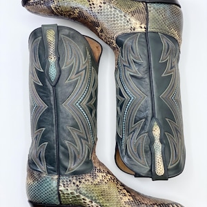 Könnte beinhalten: Cowboy-Stiefel mit Schlangenmuster am Fuß und einem Obermaterial aus dunkelblaugrünem Leder. Die Stiefel haben Ziernähte in Türkis und Gold. Die Absätze sind schwarz.