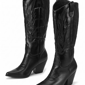May include: A pair of black leather cowboy boots. The boots have pointed toes, decorative stitching, and a mid-height block heel. The shaft features an embroidered design. The boots are set against a white background.