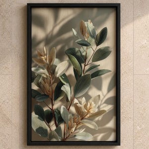 Op de afbeelding: Een ingelijst verticaal wandkunstwerk met een botanische illustratie van bladerrijke takken in gedempte groen- en beigetinten. Het kunstwerk toont zachte schaduwen die over het gebladerte vallen, wat een gelaagd effect creëert binnen een dunne zwarte lijst.