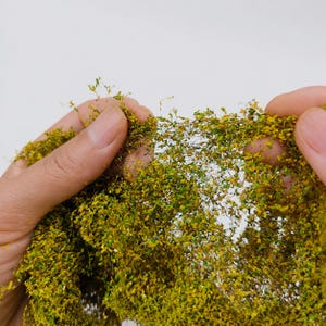 Può includere: Un foglio di fogliame per modellismo in miniatura caratterizzato da una rete densa e strutturata di rami sottili interconnessi, ricoperti da piccole foglie dai colori giallo e verde vivaci, per progetti di diorami.