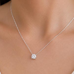May include: A delicate silver necklace featuring a single, round, clear gemstone pendant. The pendant is the focal point, suspended from a fine chain. The necklace is displayed against a neutral background, highlighting its simple elegance.