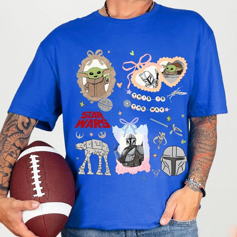 Może przedstawiać: Kr&oacute;lewska niebieska koszulka z grafiką Star Wars. Projekt zawiera obrazy Grogu, Mandalorianina i tekst "This is the Way". Inne grafiki to AT-AT walker, hełm i miecz świetlny.