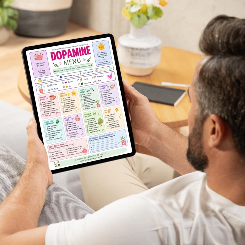 Puede incluir: Una tableta digital que muestra una colorida plantilla de planificador Dopamine Menu. La pantalla presenta secciones para comodidad, energ&iacute;a, enfoque, creatividad, conexi&oacute;n, autocuidado, naturaleza y refuerzos personales con casillas.