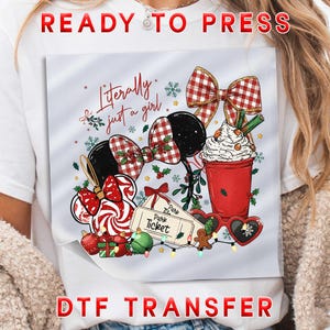 May include: A white t-shirt featuring a DTF transfer graphic with the text Literally just a girl. The design includes mouse ears with a red and white plaid bow, a red cup with whipped cream, park tickets, heart-shaped glasses, and ornaments.