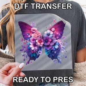 May include: A square DTF transfer sheet featuring a butterfly graphic composed of various purple, pink, and blue flowers. The text DTF TRANSFER and READY TO PRES is printed in white at the top and bottom of the image, respectively.