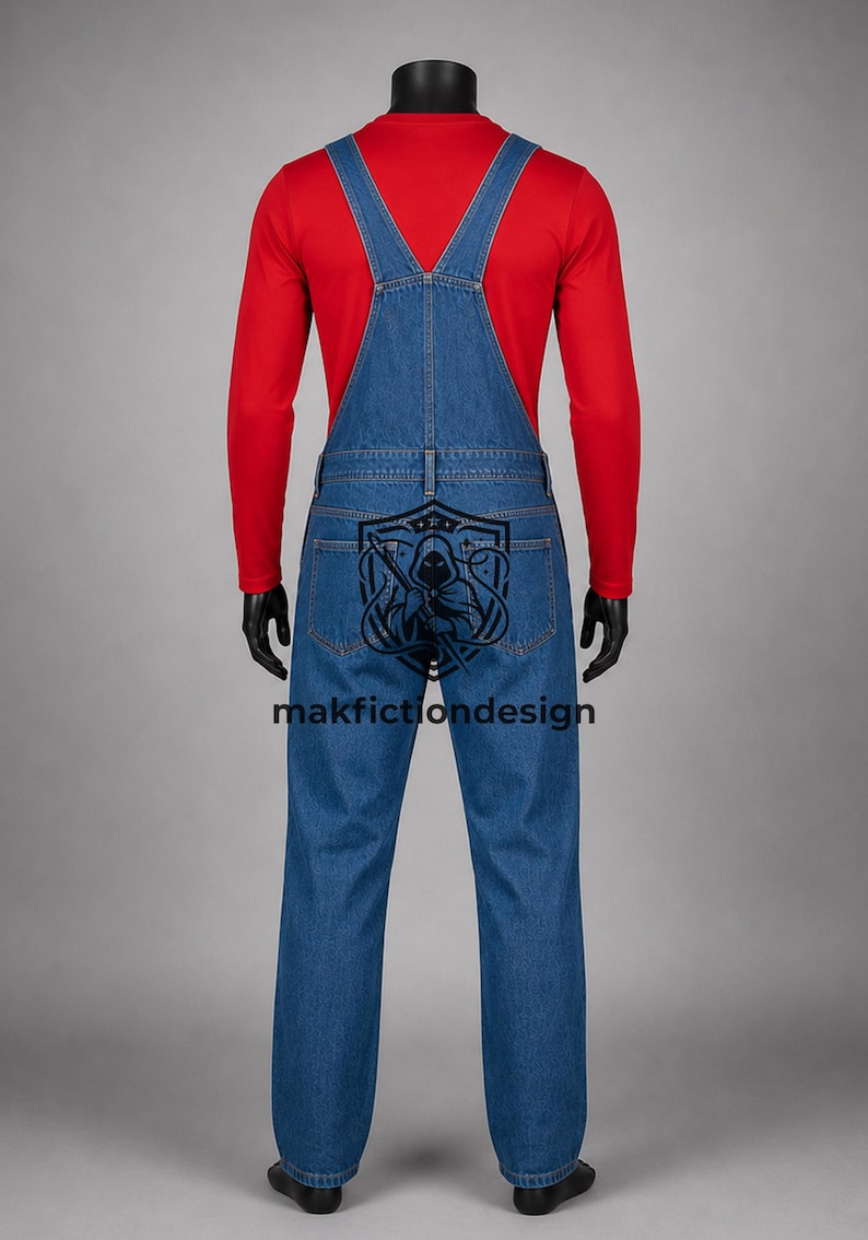 Puede incluir: Una camiseta roja de manga larga debajo de un peto vaquero azul. La parte trasera del peto presenta un estampado gr&aacute;fico negro de una figura con capucha dentro de un emblema de escudo, con el texto makfictiondesign impreso en negro.