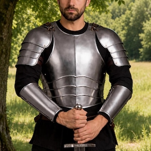 May include: A polished steel breastplate with matching shoulder pauldrons and forearm bracers worn over a black long-sleeve shirt. The metal armor features a segmented design with visible rivets and leather straps, paired with a steel sword held upright.