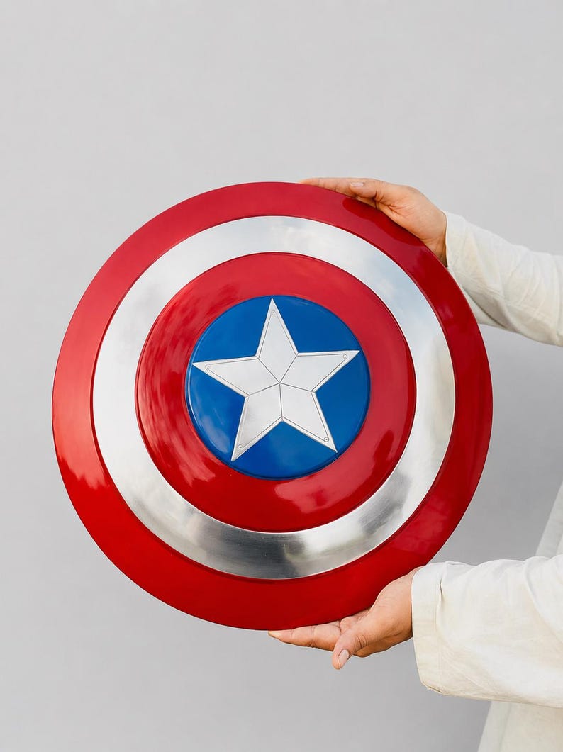 May include: A circular shield featuring a glossy red outer ring, a metallic silver middle ring, and a vibrant blue center circle. A large, five-pointed white star is centered within the blue circle, creating a bold, iconic, and symmetrical design.