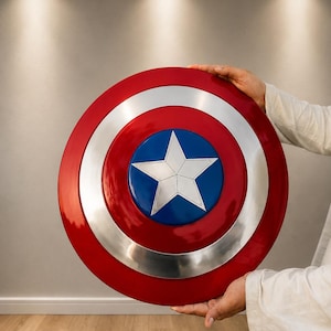 May include: A circular shield featuring a glossy red outer ring, a metallic silver middle ring, and a deep blue center circle. A large, five-pointed silver star is centered within the blue circle, creating a classic patriotic color scheme.