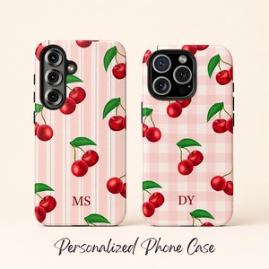 May include: Two phone cases with a cherry design. One case has a pink and white striped background, the other has a pink gingham background. Both cases feature red cherries with green leaves. The text "MS" and "DY" are visible on the cases. The text "Personalized Phone Case" is at the bottom.