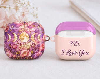 May include: Two protective cases for wireless earbuds. One case features a vibrant purple and pink floral pattern with a moon phase design. The other case is light pink with a solid purple top lid and the text PS: I Love You printed in purple.