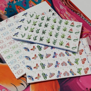 Nature inspired American Mahjong tile set with woodland illustrations, butterfly dot tiles, pine branch bam tiles, firefly mason jar craks, mushroom flower tiles, compass wind tiles, whimsical forest Mahjong set, cottagecore Mahjong tiles, collectible Mahjong game set, luxury Mahjong tiles, aesthetic board game décor, botanical Mahjong collection, artistic Mahjong gift for nature lovers and cozy game nights