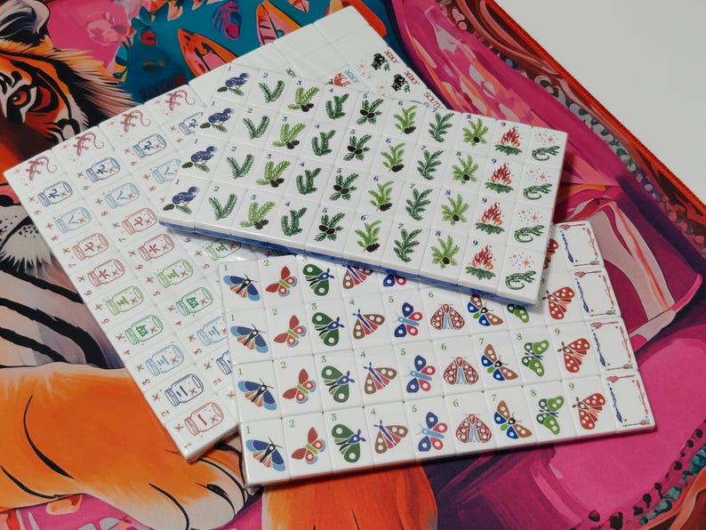 Nature inspired American Mahjong tile set with woodland illustrations, butterfly dot tiles, pine branch bam tiles, firefly mason jar craks, mushroom flower tiles, compass wind tiles, whimsical forest Mahjong set, cottagecore Mahjong tiles, collectible Mahjong game set, luxury Mahjong tiles, aesthetic board game décor, botanical Mahjong collection, artistic Mahjong gift for nature lovers and cozy game nights