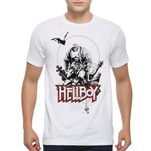 May include: A white short-sleeved t-shirt featuring a black and white graphic illustration of the character Hellboy surrounded by various objects, including a bat and a skull. The word HELLBOY is printed in large, bold, dark red letters below.
