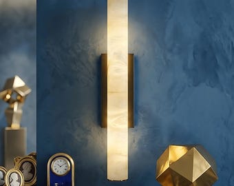 May include: A vertical wall sconce featuring a long, cylindrical, translucent white shade with a marbled texture. The light fixture is mounted on a rectangular black base and emits a soft, warm glow from within the illuminated tube structure.