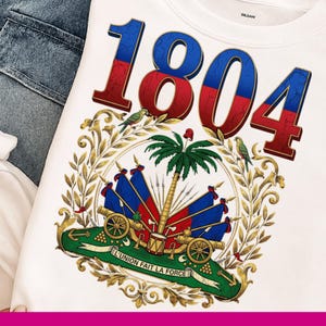 May include: White sweatshirt featuring the number "1804" in red and blue, above a detailed emblem. The emblem includes a palm tree, flags, cannons, and the text "L'UNION FAIT LA FORCE".