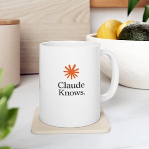 May include: A white ceramic mug featuring an orange sunburst icon above the black text "Claude Knows." The mug has a standard cylindrical body with a curved handle on the right side, presented in a clean, minimalist style for daily beverage use.
