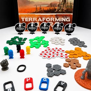 May include: A Terraforming Mars board game set featuring a game box, five black circular pass markers, various colored player tokens, hexagonal resource tiles in green, white, gray, and orange, a gray rocket ship on a red base, and four rectangular markers.