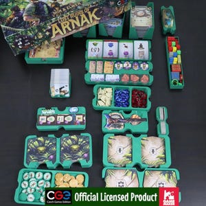 May include: A board game set titled Lost Ruins of Arnak featuring green plastic organizers filled with various game components including cards, small wooden cubes in red, yellow, blue, and green, white stone tokens, blue crystals, and red rubies.