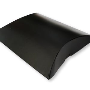 May include: A matte black pillow box made of cardstock with a curved, rectangular shape. The container features folded ends that create a rounded, convex profile, providing a sleek and simple enclosure for small items or gifts.