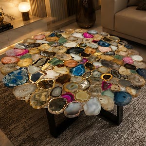 May include: A round coffee table with a mosaic top made of various colorful agate slices. Each slice is outlined in gold and set on a black metal base. The table's design incorporates shades of blue, pink, and yellow.