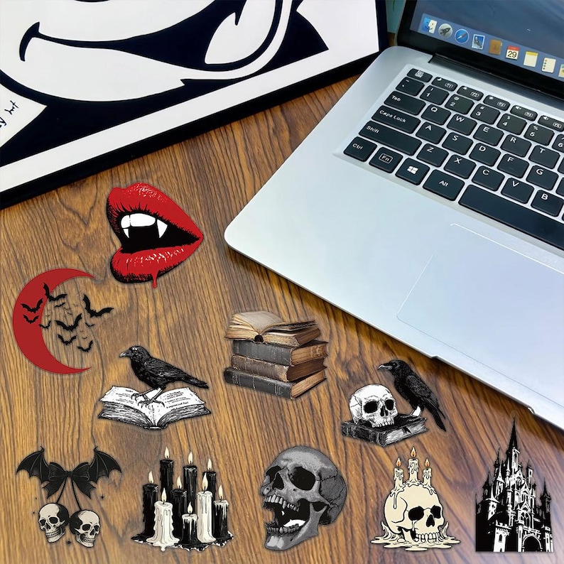 May include: A collection of gothic-themed stickers featuring red vampire lips, a red crescent moon with bats, a raven on an open book, a stack of old books, a raven on a skull, bat-winged skulls, black candles, a human skull, and a castle.