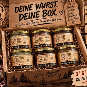 Könnte beinhalten: Ein Geschenkkarton aus Pappe mit sechs Gläsern Wurstaufstrich, jedes mit einem beigen Etikett und dem Logo Fleischerhandwerk Hoffmann. Der Deckel zeigt den Text DEINE WURST. DEINE BOX. sowie einen hölzernen Anhänger mit handschriftlichen Notizen.