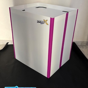 Op de afbeelding: Een witte vierkante behuizing met verticale magentakleurige strepen op de hoeken en een Spinbox-logo op het voorpaneel. De structuur heeft een vlak bovenoppervlak met zwarte accenten op de hoeken en een strak, rigide ontwerp.