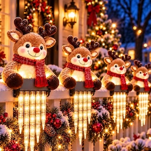 May include: A row of four plush reindeer decorations with brown fur, red noses, and red scarves, each mounted on a black base with hanging icicle-shaped LED lights that emit a warm glow, positioned along a white fence railing during the winter.