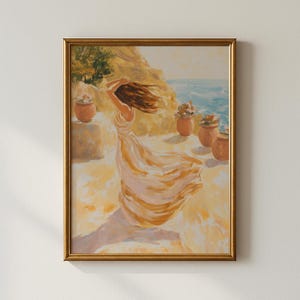 Op de afbeelding: Een ingelijst schilderij toont een vrouw in een zwierige jurk met wapperend haar. Het kunstwerk heeft een warm kleurenpalet van geel, oranje en blauw, met een kustlandschap en terracotta potten.