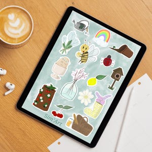 Peut inclure: Illustration numérique sur une tablette avec divers autocollants sur le thème du jardin. Les autocollants comprennent un arrosoir, des fleurs, une abeille, un arc-en-ciel, une coccinelle, un nichoir, un citron et une botte avec des fleurs. La tablette est sur une surface en bois.