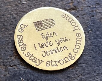 May include: A brass coin with an engraved American flag, the text "Tyler I love you. Jessica be safe. stay strong. come home" and a hammered texture.