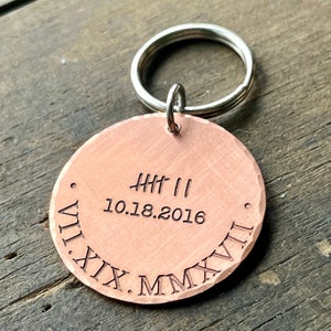 May include: Copper keychain with a round tag engraved with Roman numerals, the date 10.18.2016, and the text "HHH II".