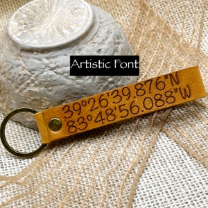 May include: A brown leather keychain with a brass ring and engraved coordinates: 39&deg;26'39.876"N 83&deg;48'56.088"W.