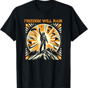 May include: Black t-shirt with a graphic featuring a figure in a spacesuit raising a fist atop a mountain, surrounded by parachutes. The text "FREEDOM WILL RAIN" is printed above the figure in orange.